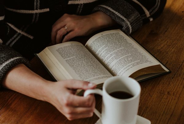 A person sitting on the floor with a book and a cup of coffee